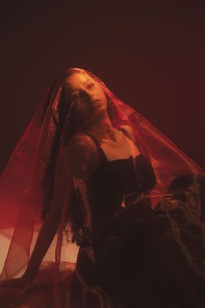 Dramatic red-lit portrait of a woman with expressive movement against a dark background