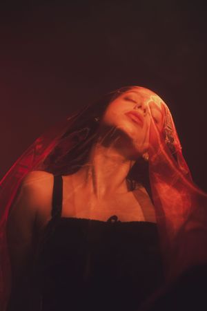 Dramatic red-lit portrait of a woman looking upward in a dark cinematic setting