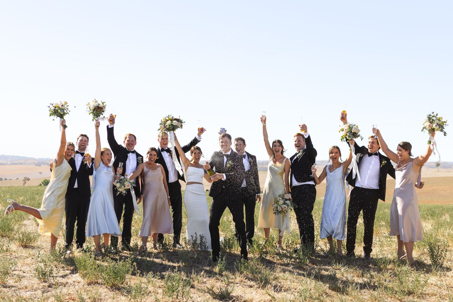 bridal party spraying champagne on top of hill at nsw country wedding