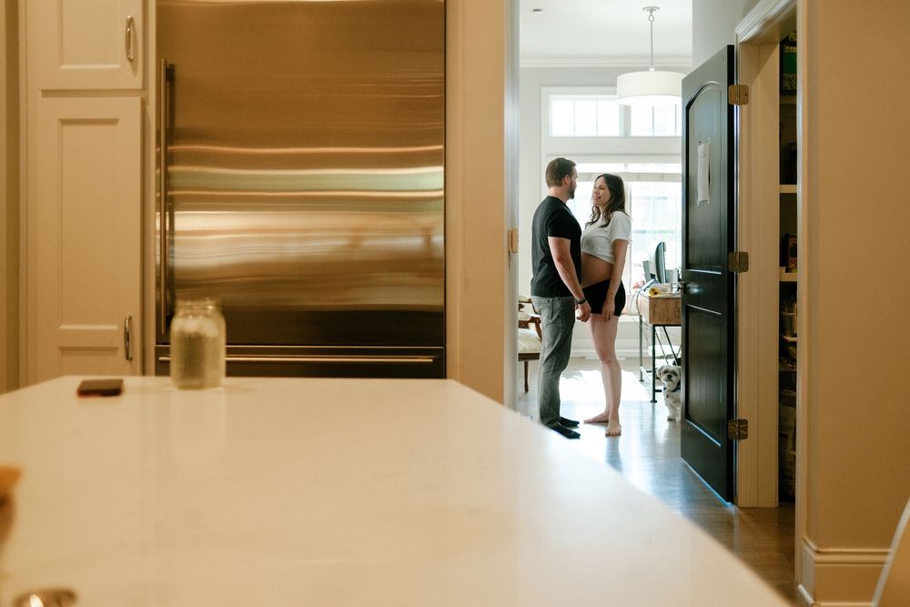Couple sharing a romantic moment in a modern kitchen with stainless steel refrigerator and elegant white countertops.