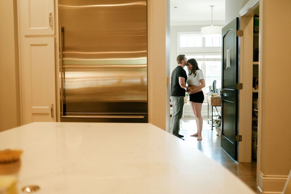 Couple sharing a tender moment in a modern kitchen with stainless steel refrigerator and elegant white countertops.