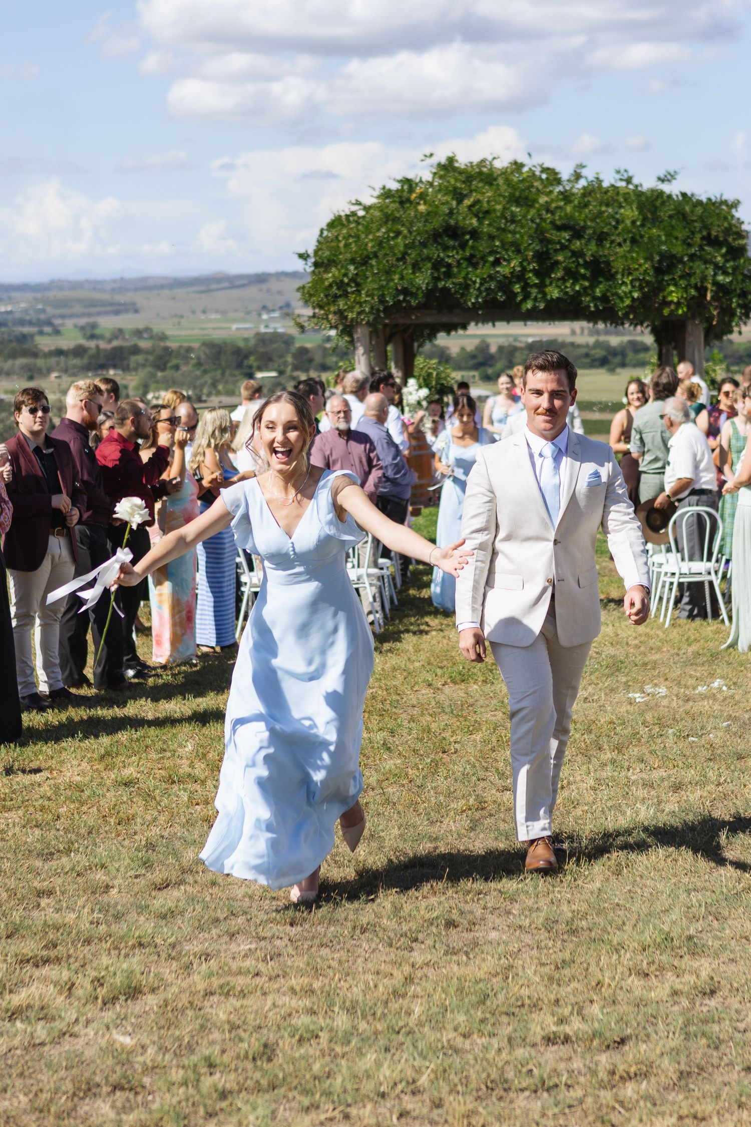 Groomsmen in cream suit and bridesmaid in blue dresses smiling at Two Rivers Winery Wedding in Denman