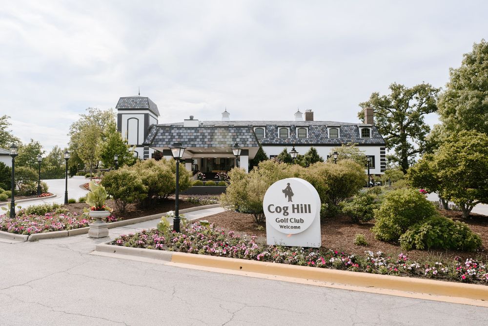 Cog Hill Golf & Country Club entrance sign surrounded by colorful flower gardens and manicured landscaping in Lemont, Illinois.
