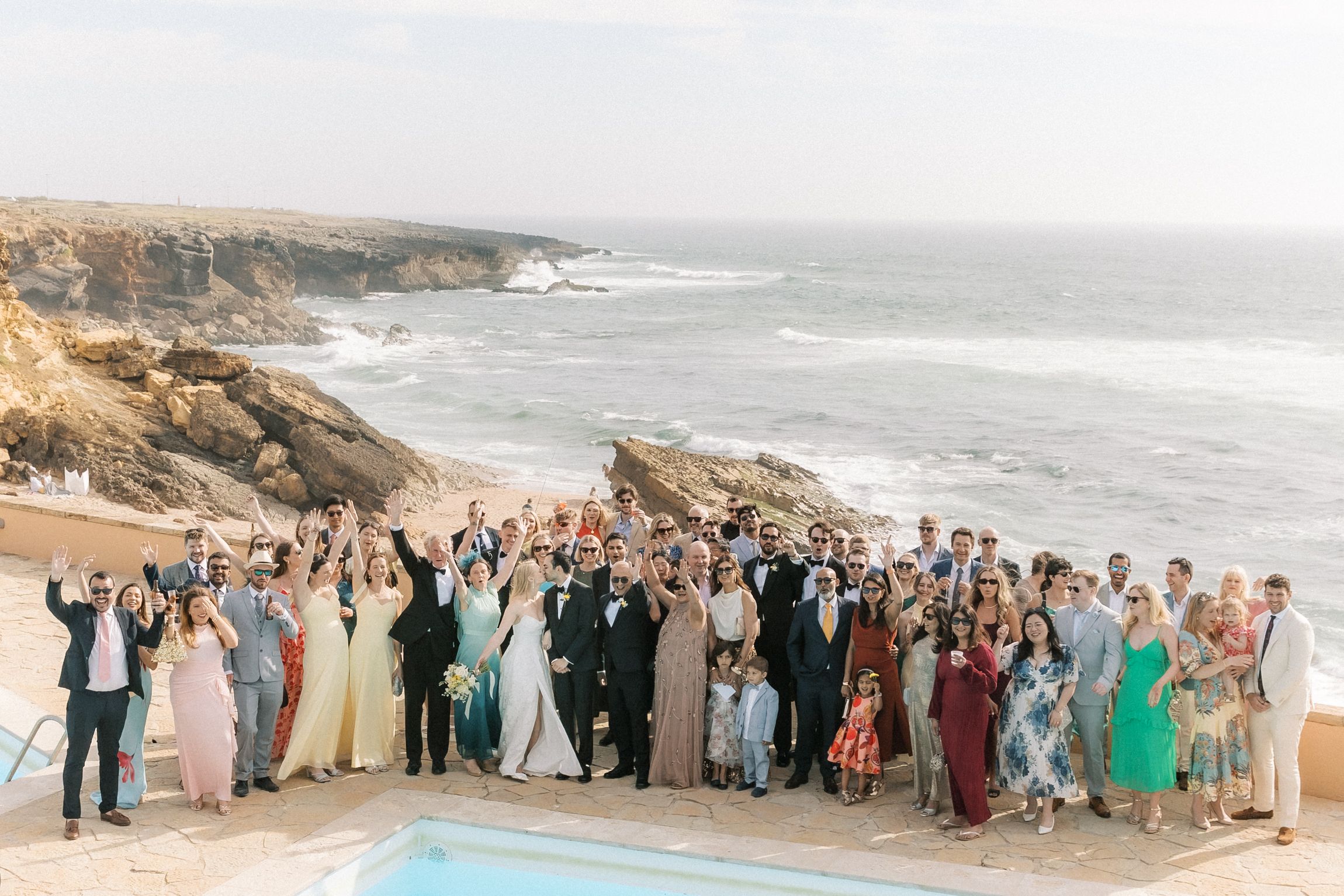 Wedding guests celebrating together overlooking the Atlantic Ocean after a destination wedding in Cascais, Portugal.