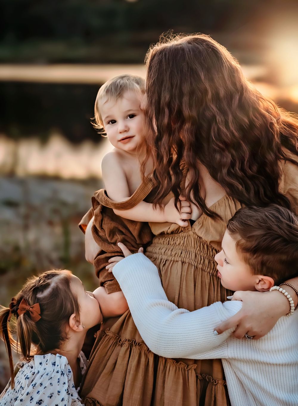A tender family moment captured at sunset with warm golden light illuminating intimate embraces and gentle interactions.