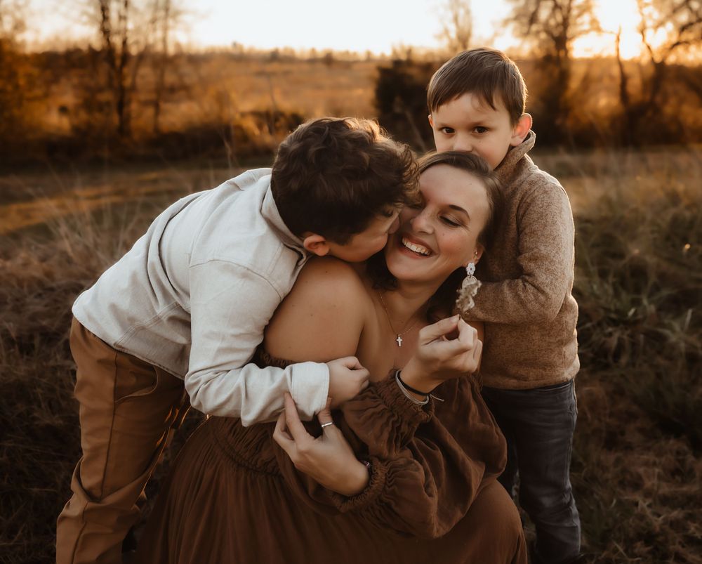 Family embracing in a golden field during sunset.