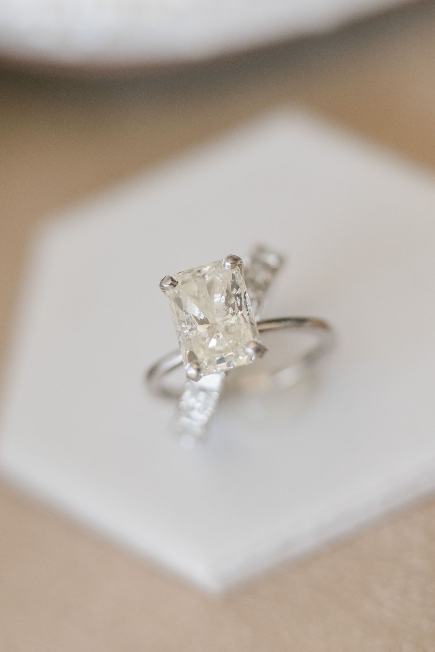 Elegant solitaire engagement ring featuring a large radiant cut diamond set in a thin silver band displayed on a white hexagon box.