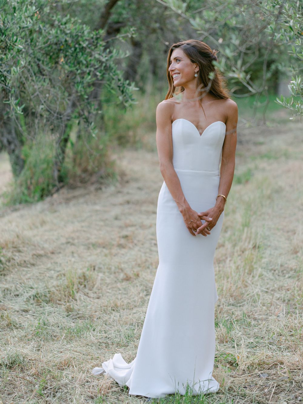 Classic strapless white wedding dress with fitted silhouette in an outdoor garden setting.