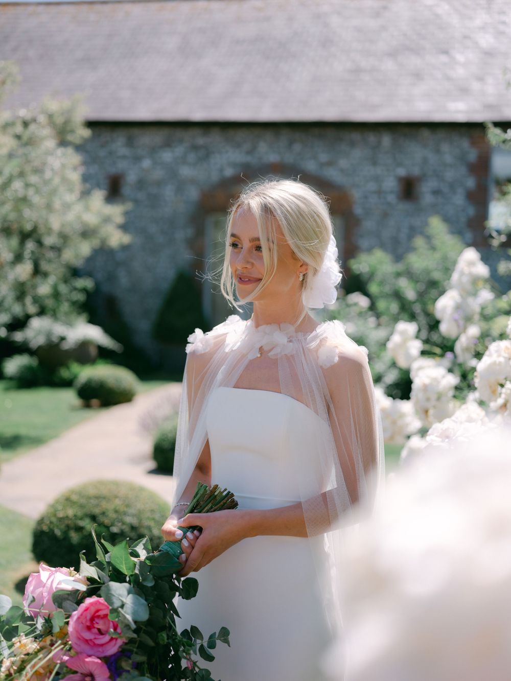 Ethereal bridal portrait featuring a modern white gown with sheer cape detail.