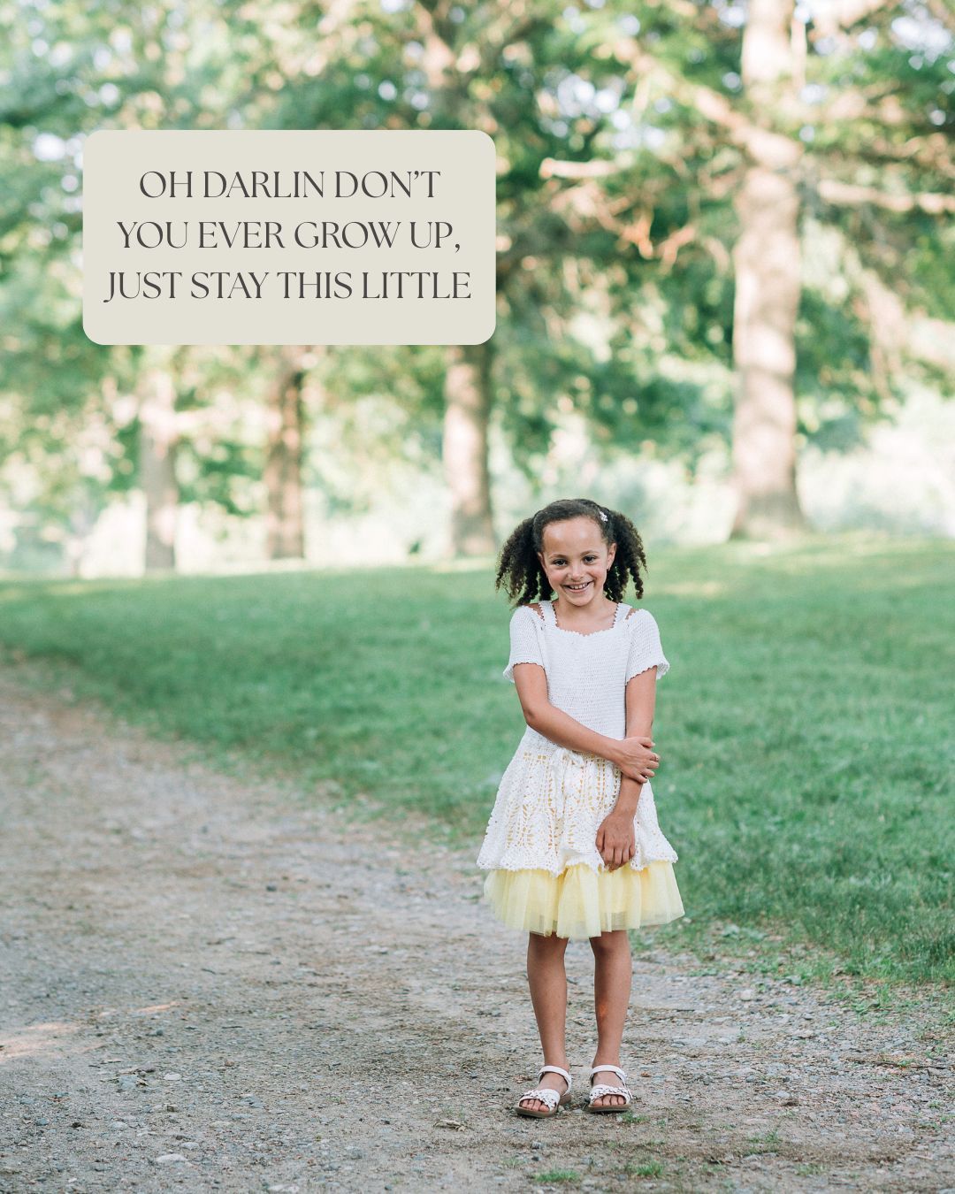 Young girl in white top and yellow tutu skirt smiling on a tree-lined path with inspirational quote overlay.