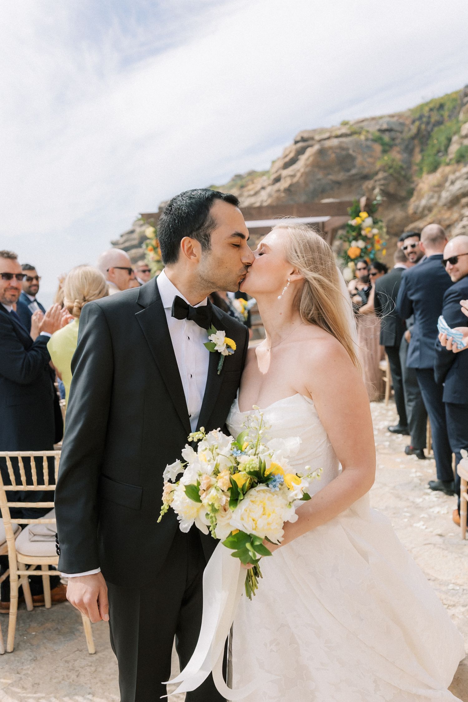 Newlyweds celebrating with a kiss after their wedding ceremony overlooking the Atlantic Ocean at Arriba by the Sea.