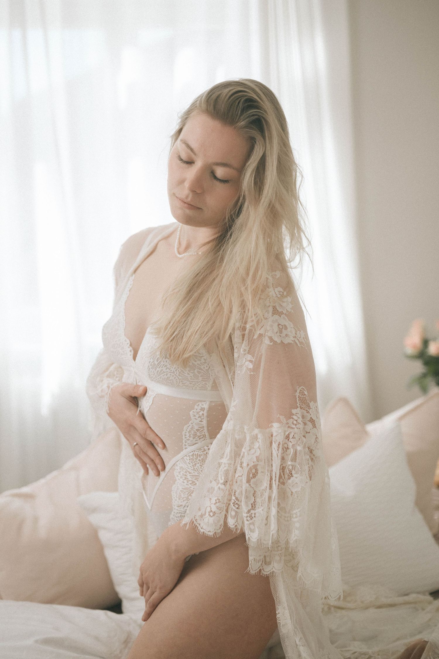 sinnliches Portrait einer auf dem Bett sitzenden Frau mit verschwommener im Tageslichtstudio in Buxtehude, Altes Land