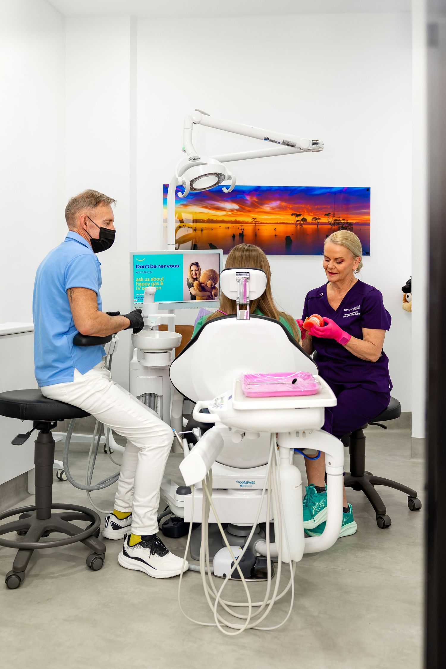 Portrait of a physiotherapist performing an ultrasound on patient's pelvis and pointing at the computer screen