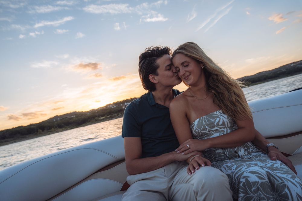 Romantic couple sitting close together on a luxury yacht at sunset, sharing an intimate moment.
