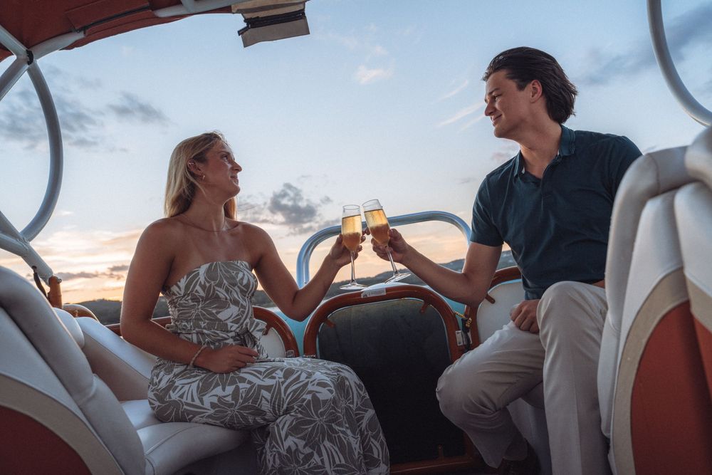 Couple toasting champagne glasses on a luxury boat at sunset, enjoying a romantic evening cruise together.