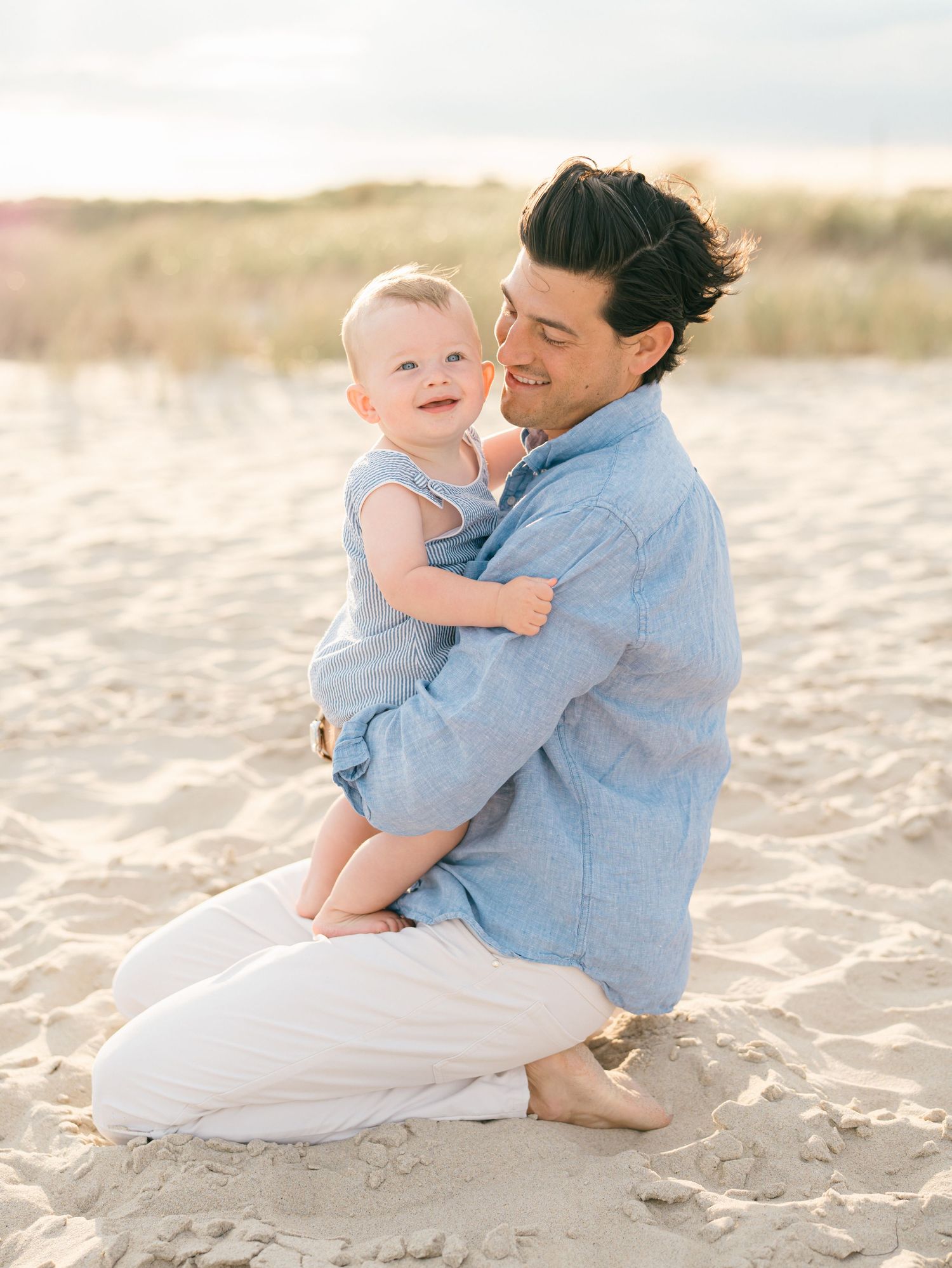 A father snuggles his young son on the sandy beach at the southern pavilion in spring lake nj.