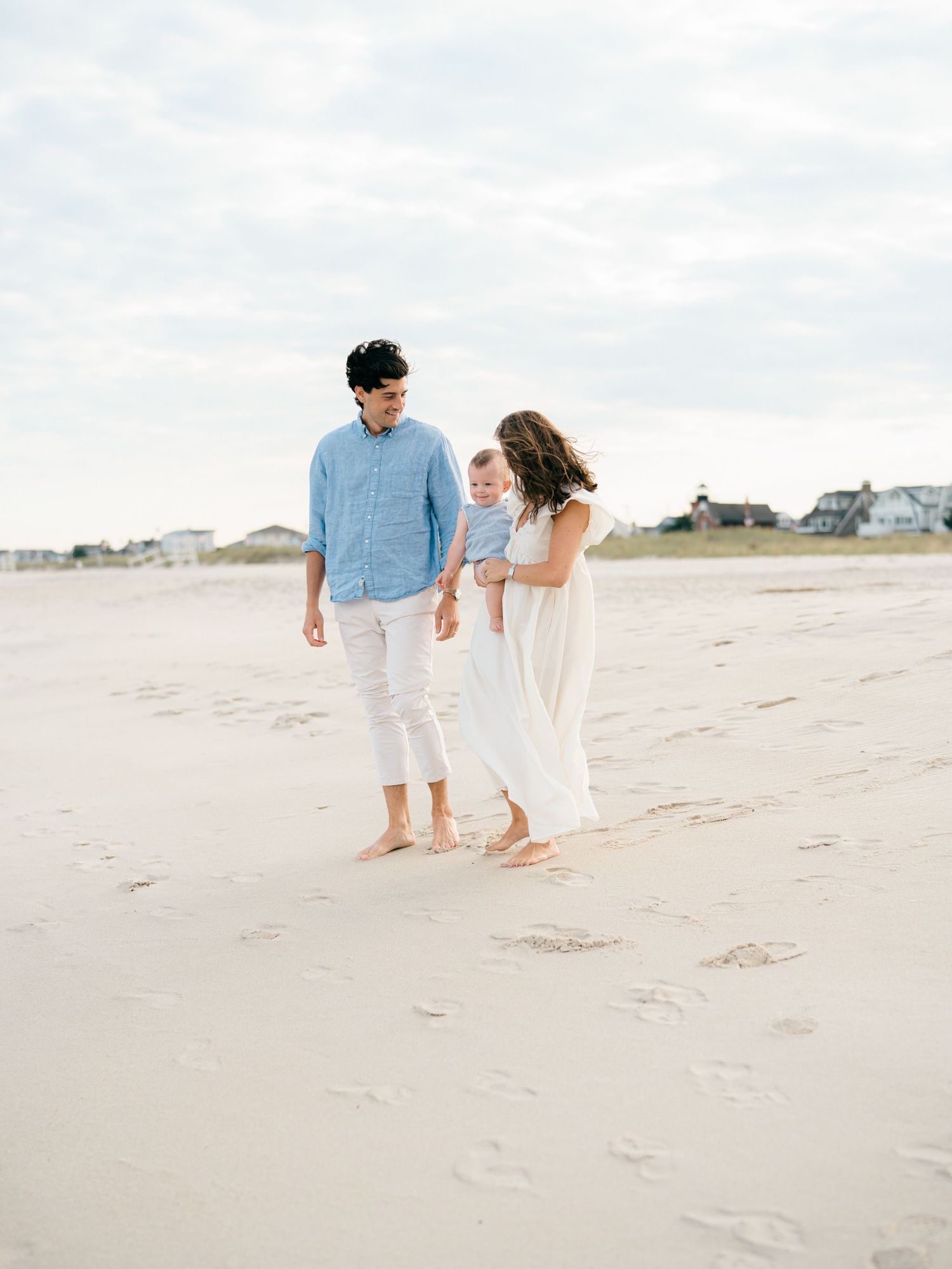 A family of 3 looks out at the ocean on the jersey shore during a nj family photo session.