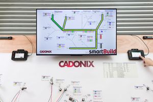Cadonix smartBuild software displayed on a monitor showing a network diagram above a demonstration wiring board.