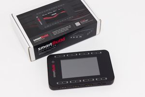 Professional product photo | Cadonix SmartBuild device with black casing and LCD screen displayed next to its retail packaging box.