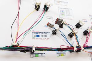 Complex automotive wire harness assembly with colorful wires, connectors, and components laid out on a white board.