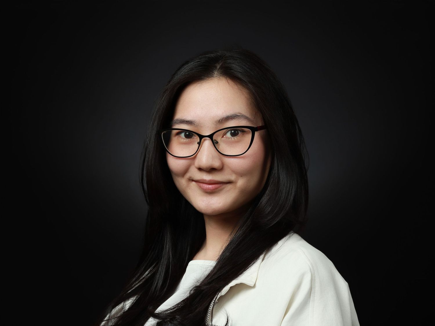 Млада жена с очила и бяло сако на тъмен фон — портрет за кариерен профил