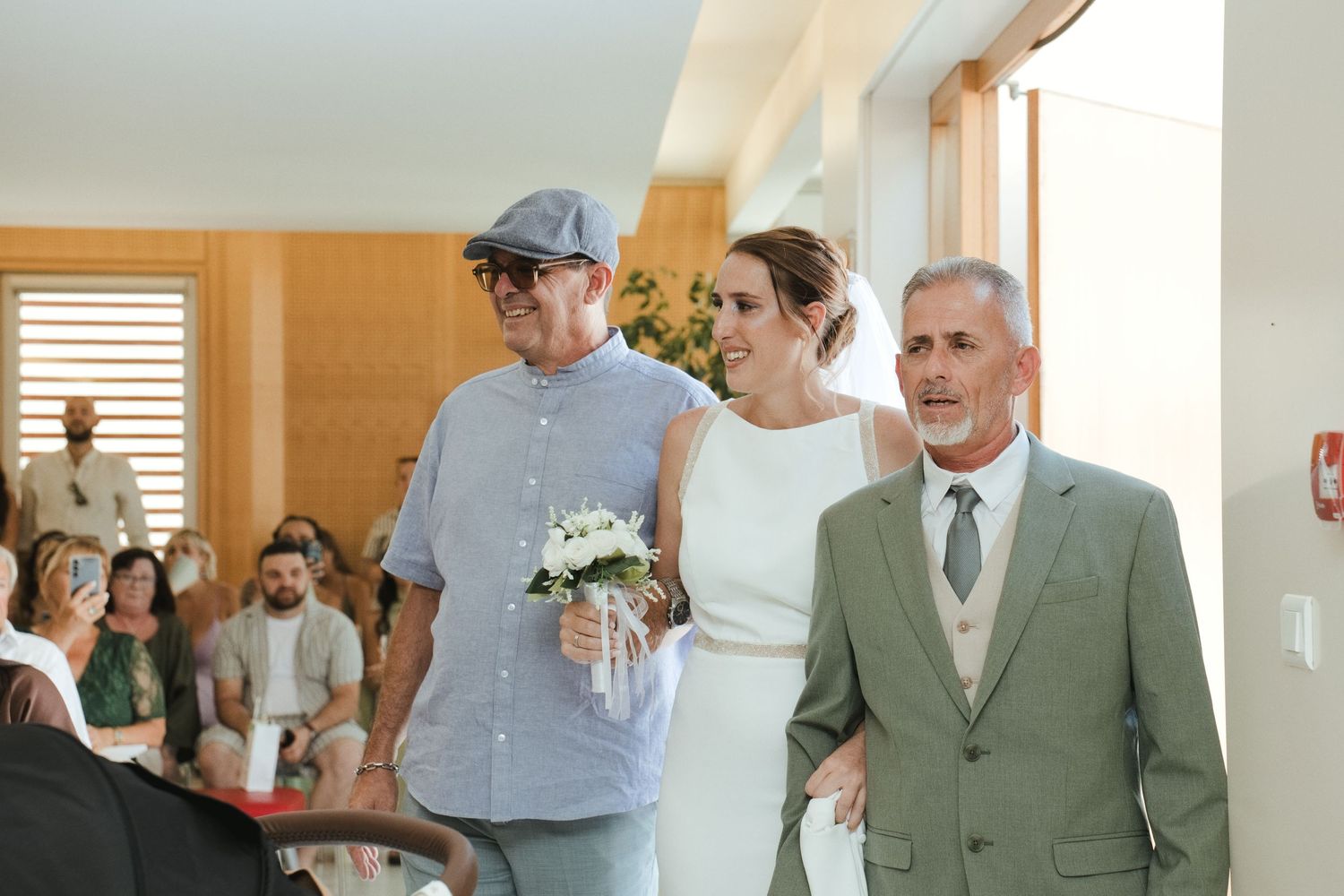 La mariée entre dans la salle de cérémonie accompagnée de deux proches.