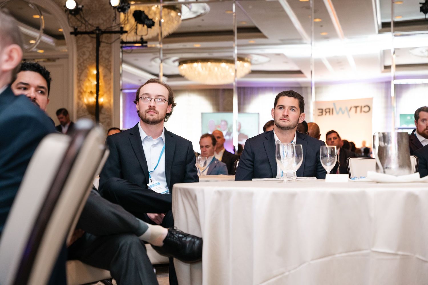 Business professionals attentively listening at a corporate conference event in a modern venue.