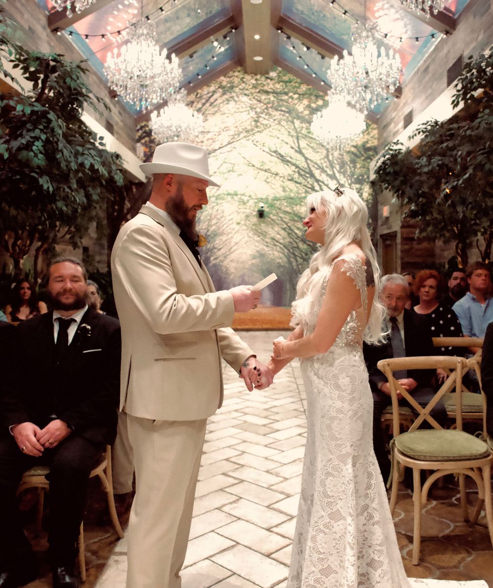 Bride and groom exchange vows in stunning indoor garden wedding venue with crystal chandeliers.