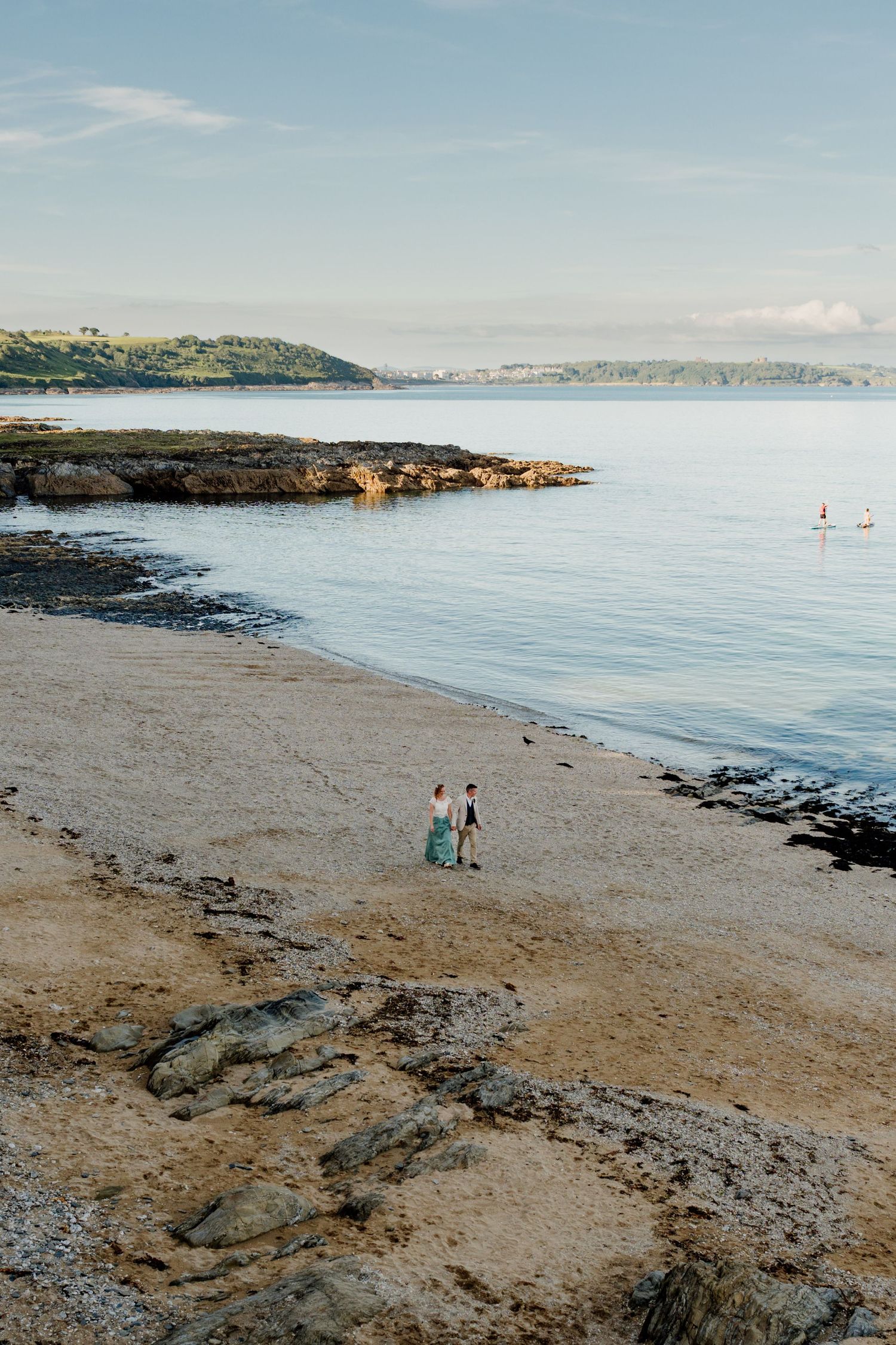 Couple walking on a sandy beach cove overlooking falmouth bay