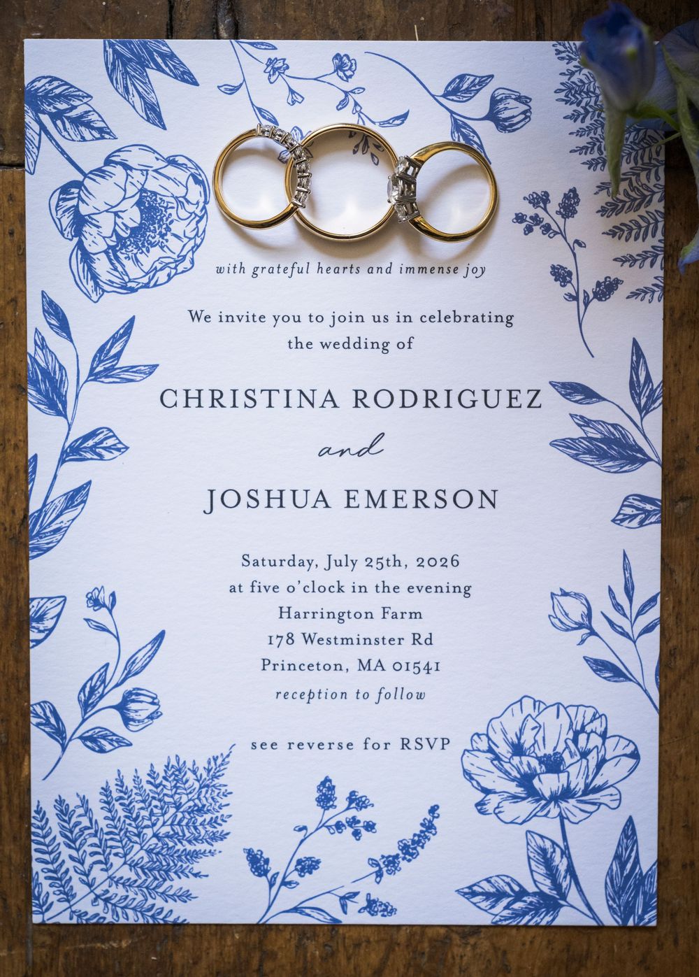 Blue floral wedding invitation for Christina Rodriguez and Joshua Emerson with gold rings at Harrington Farm Princeton MA.