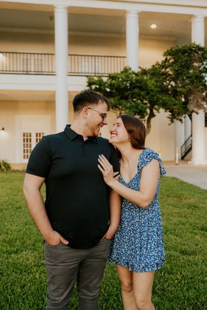Happy couple sharing a romantic moment outdoors near a white columned building at sunset.