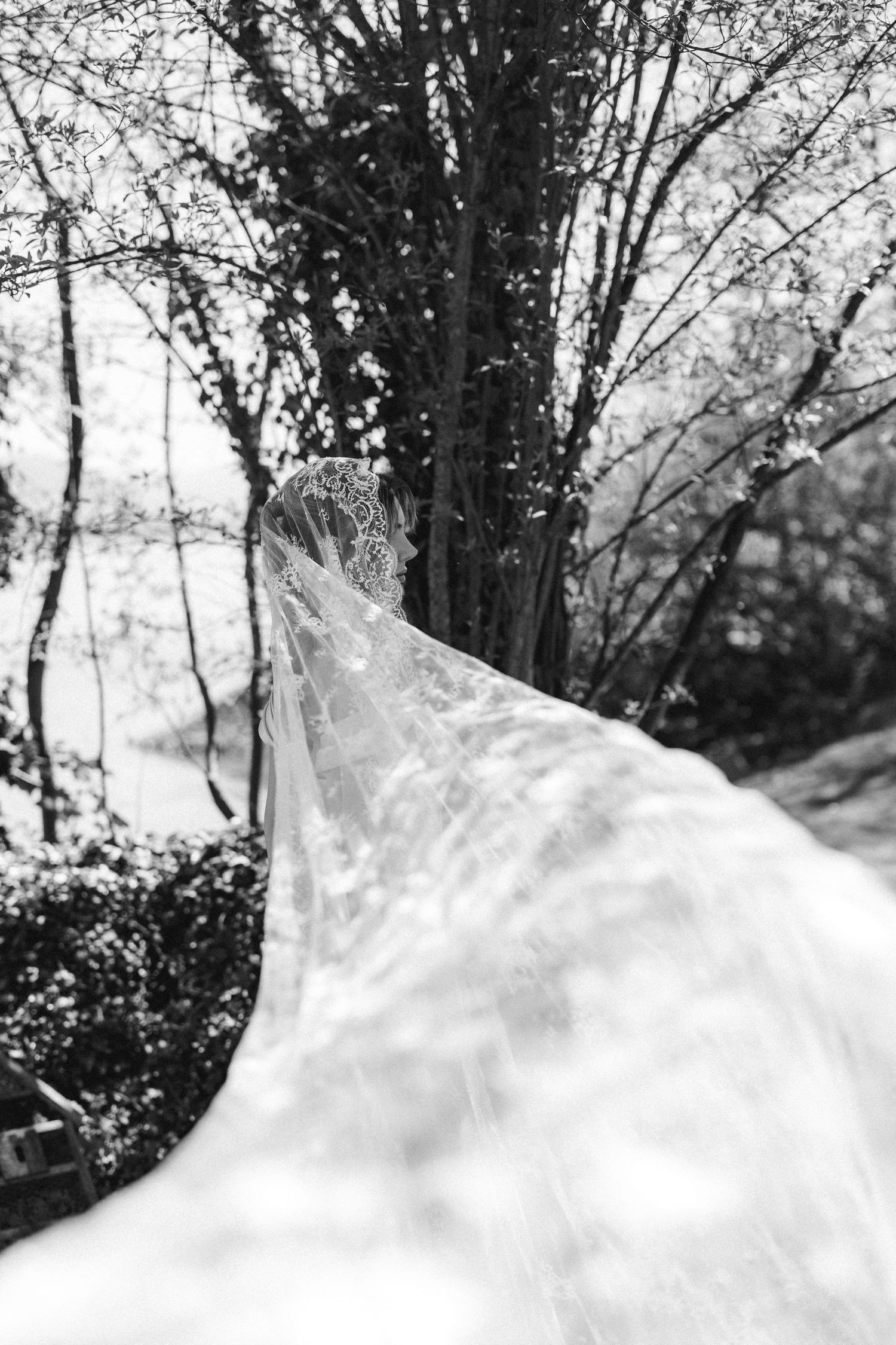 Black and white photo of a bride in a white gown and veil holding a beaded bag.