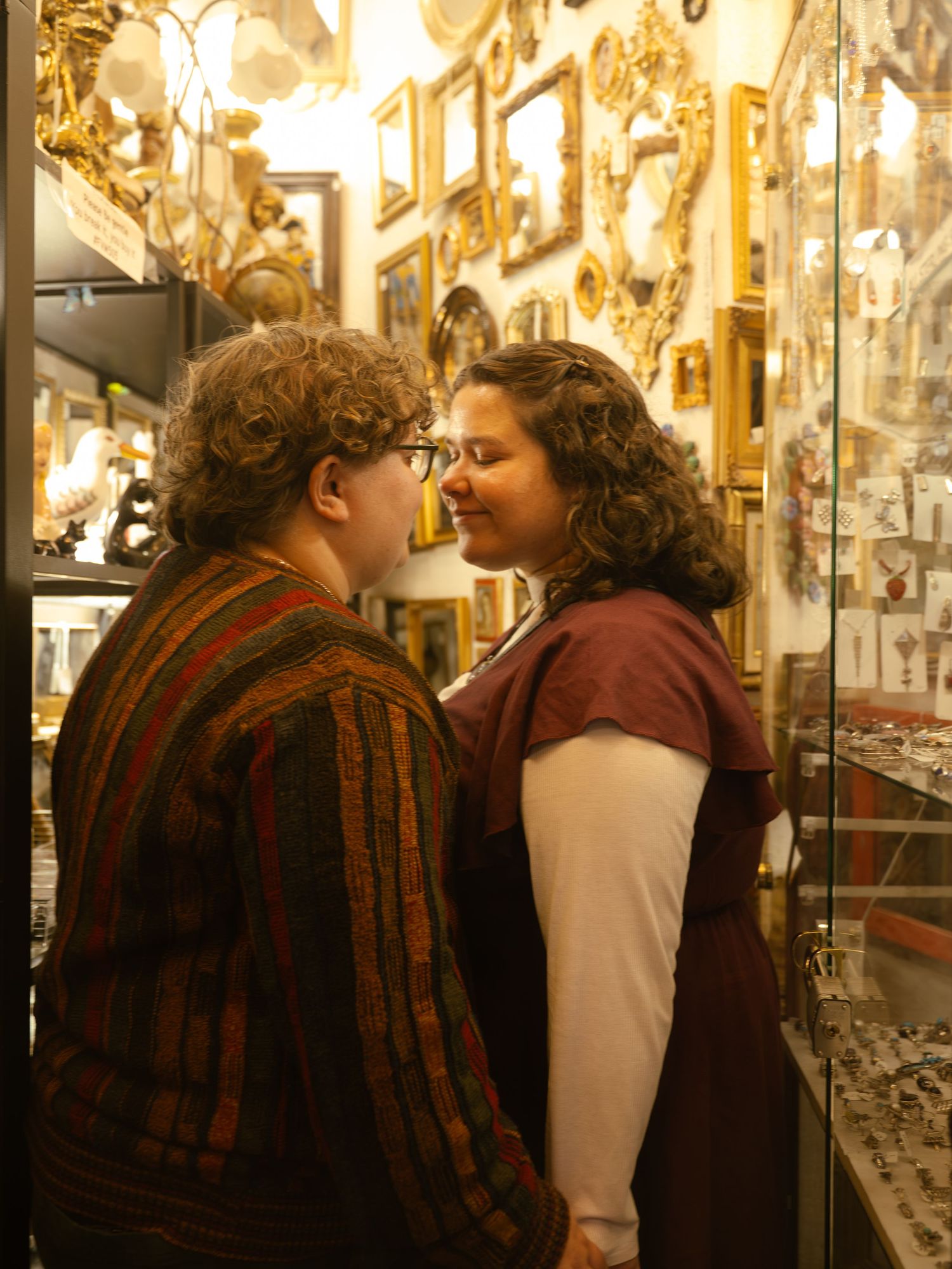 Couple sharing a romantic moment in an antique shop filled with vintage frames and jewelry displays.