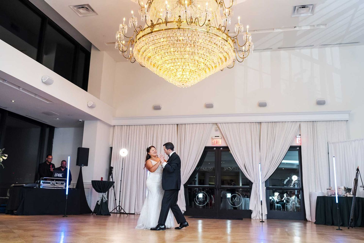 Bride and groom share first dance under grand crystal chandelier at the view wedding venue
