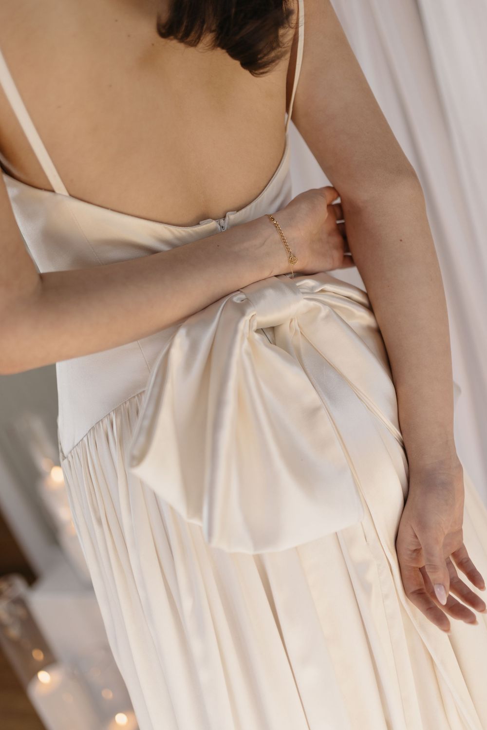 Close-up of bride in ivory satin wedding dress with large bow detail at the back.