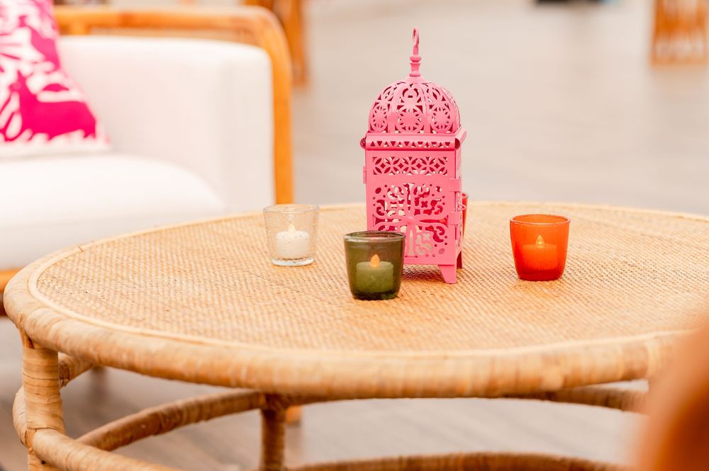Pink Moroccan lantern centerpiece with colorful votive candles on a round rattan coffee table.