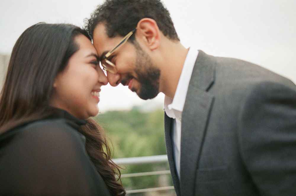Romantic couple sharing an intimate moment, touching foreheads and smiling outdoors on a balcony.