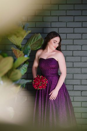 Matric learner holding a bouquet of red roses to match her purple dress.