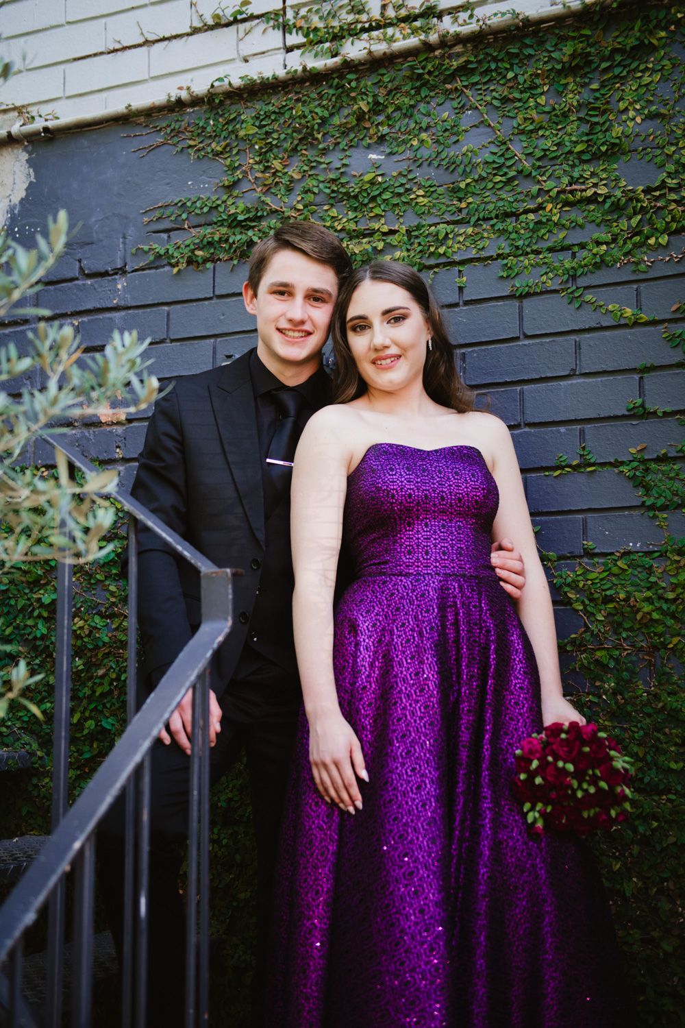 Matric dates posing in an outdoor urban setting with brick textures