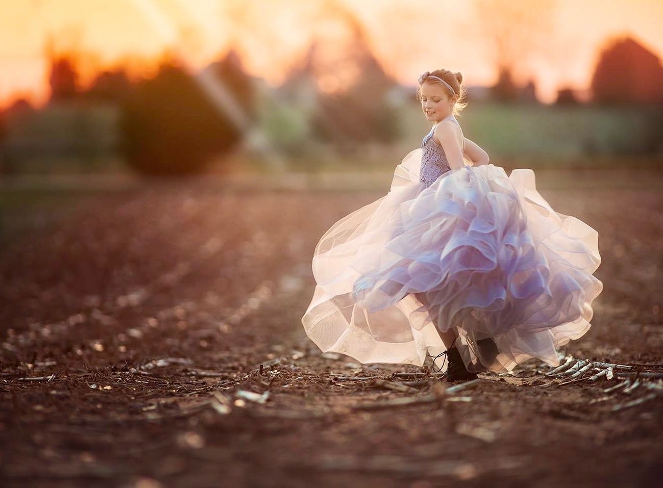 Young girl dancing in a sunlit field at sunset during an outdoor portrait session in Salem County, New Jersey.