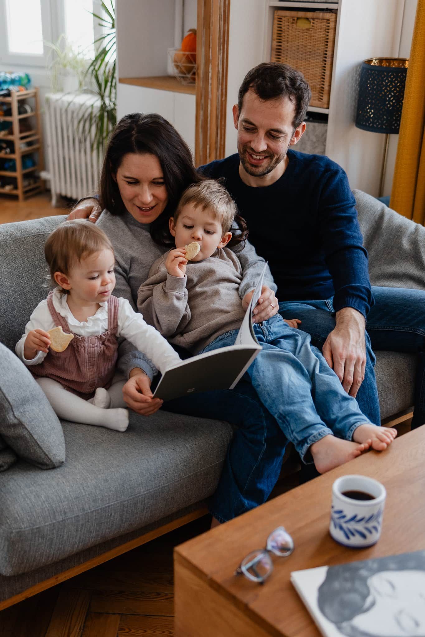 Famille qui feuillette son livre photo de famille imprime apres une seance a domicile a Lille