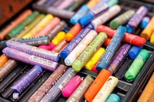 Colorful collection of oil pastels in various shades arranged in a black art supply box.