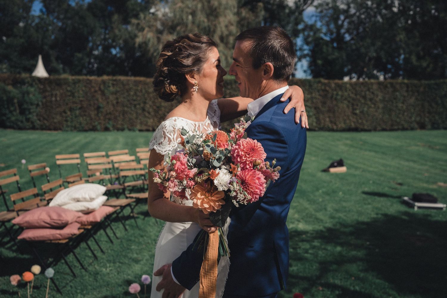 Bride and groom share an intimate kiss outdoors, bride holding a colorful bouquet.