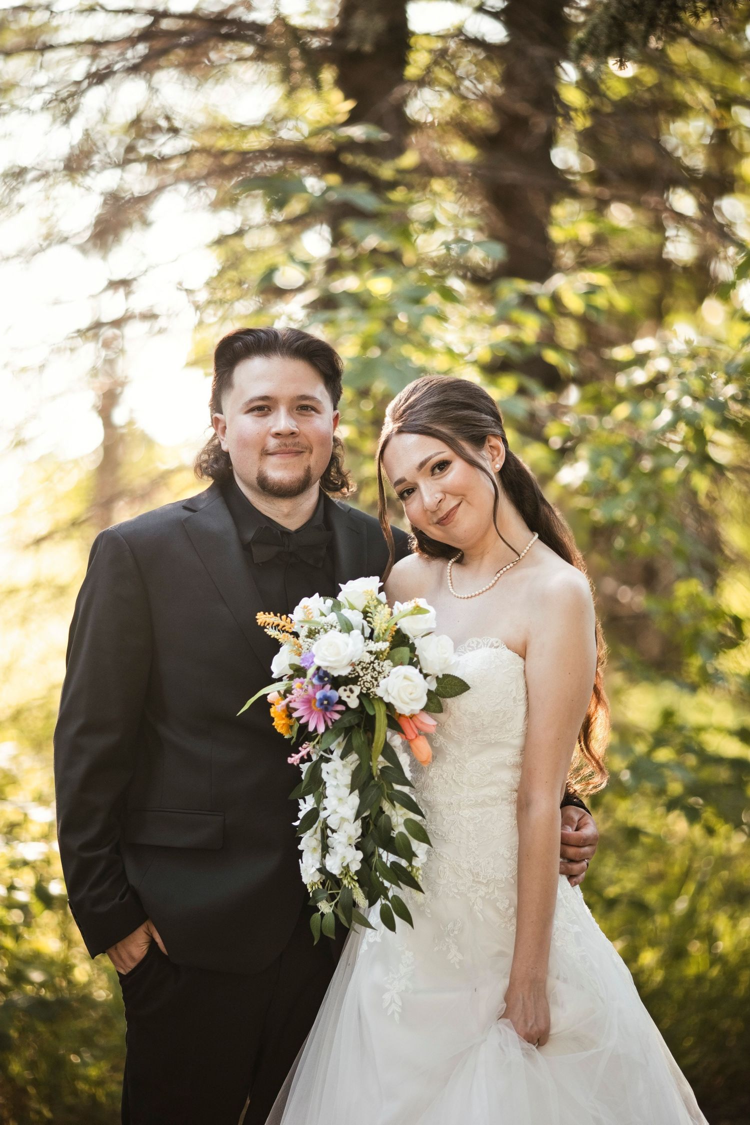 A bride in an elegant white lace wedding dress with a veil and statement necklace poses thoughtfully in a dressing room. Hawthorne Estates