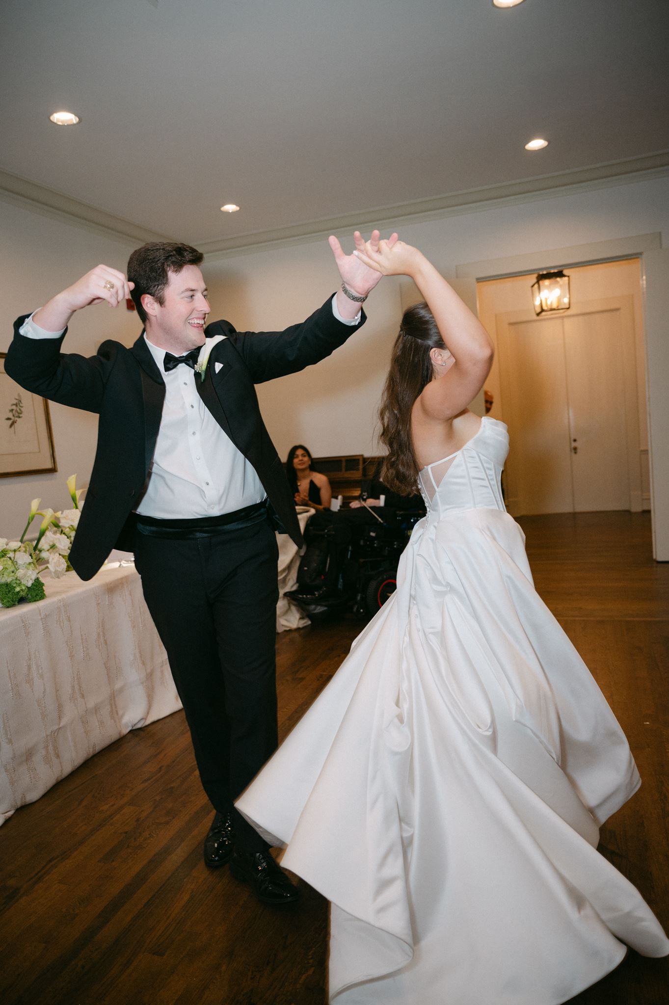 Groom twirling bride on dance floor.