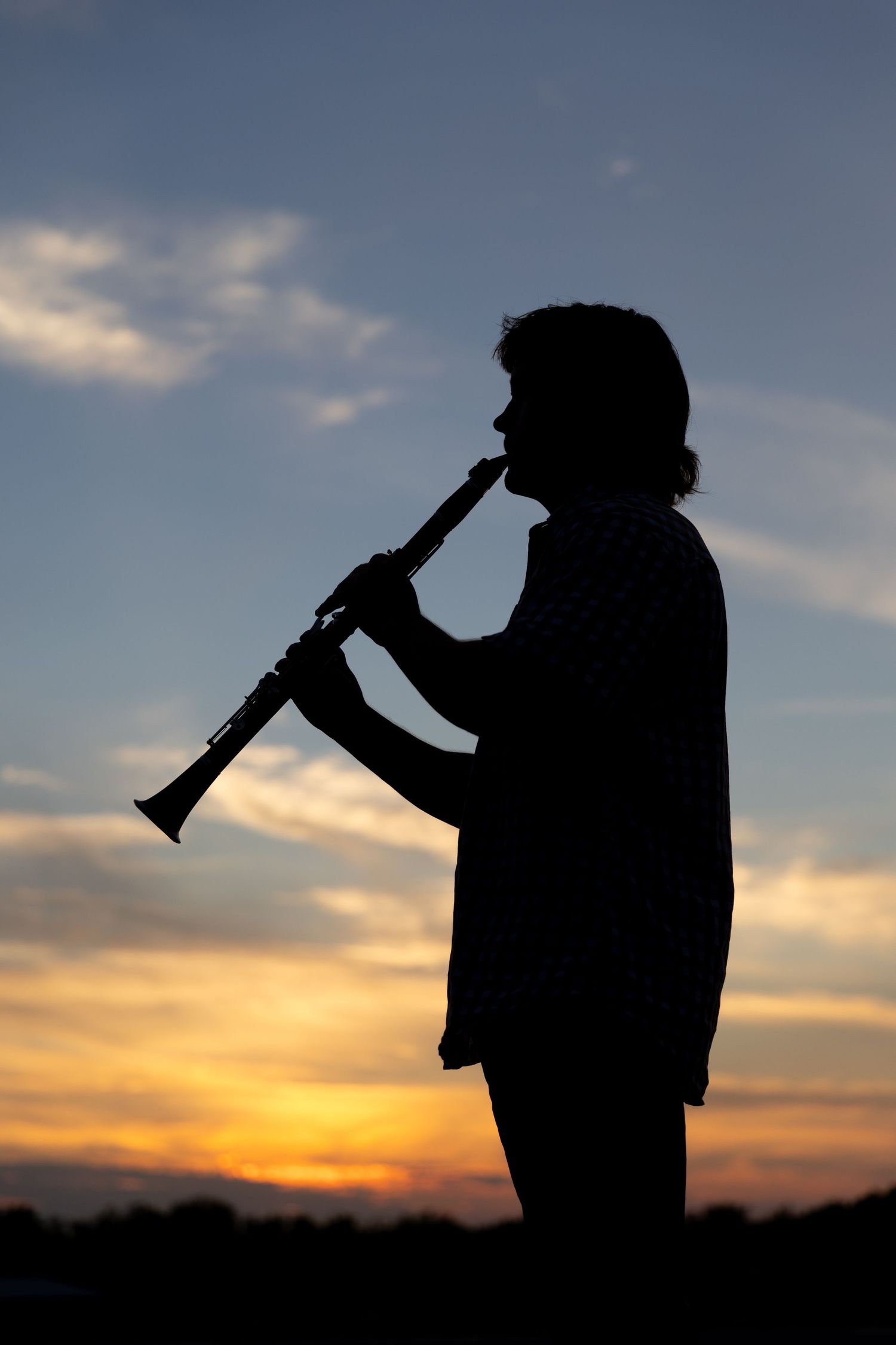Silhouette image of a high school senior boy who plays clarinet in band.