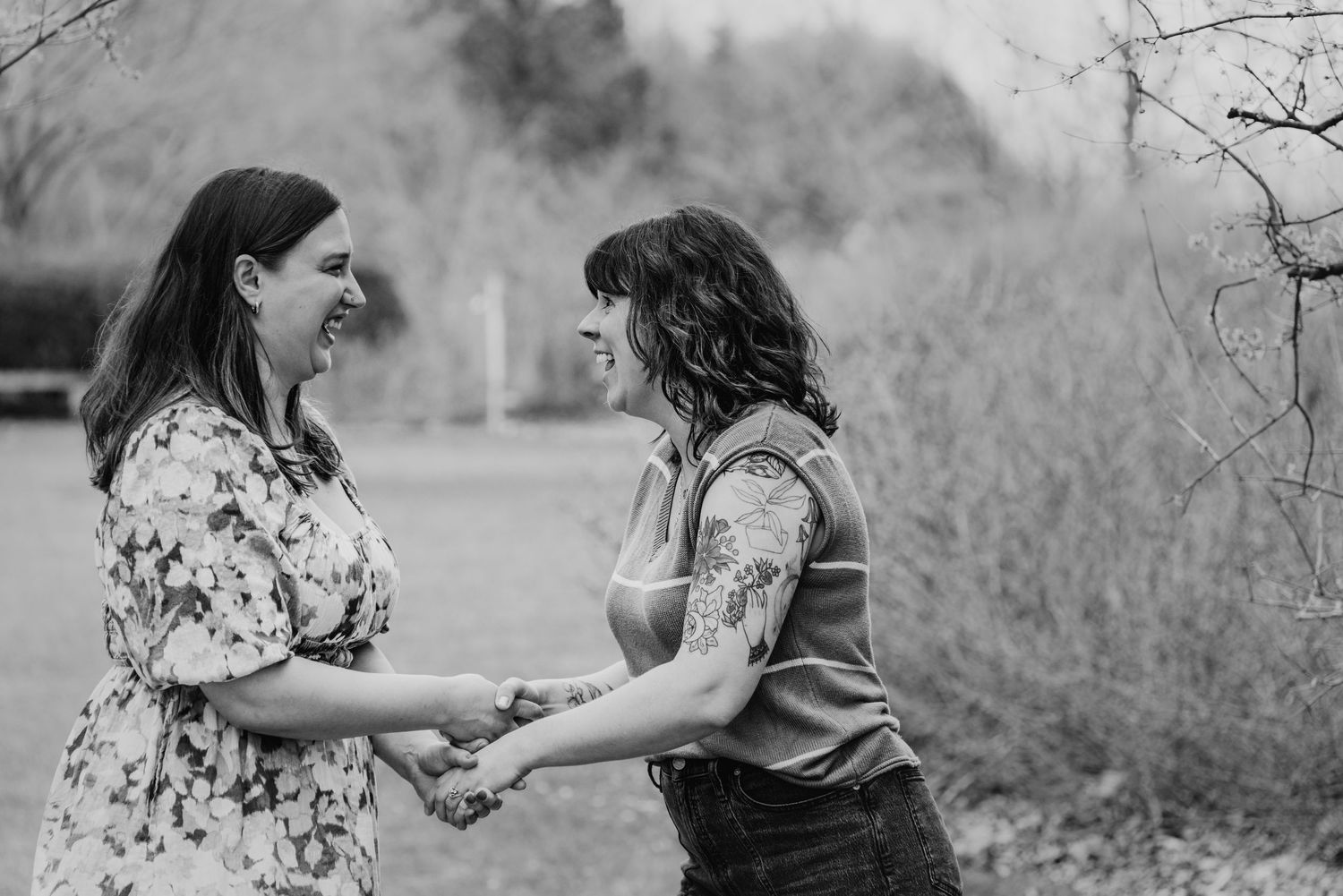 Two women embrace romantically outdoors, surrounded by a dreamy swirling bokeh effect of blossoming trees.