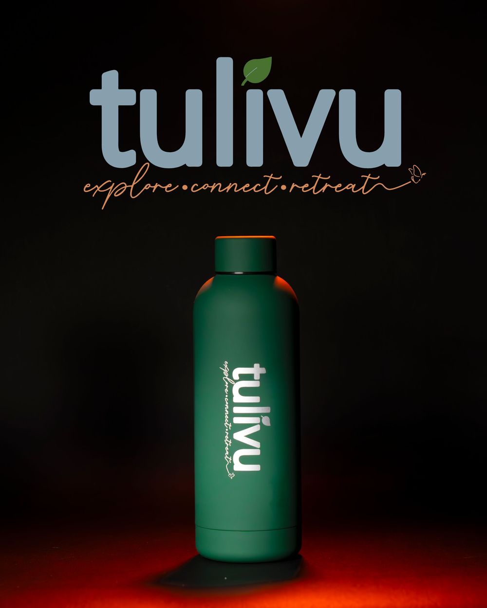 Green tulivu branded water bottle with explore connect retreat tagline on dark background.