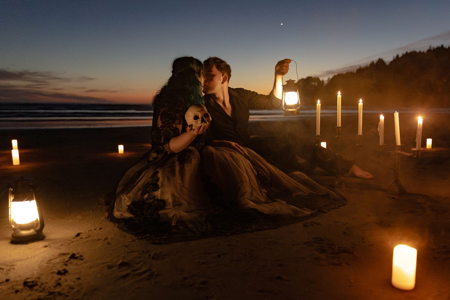 Couple holding skull and lantern by candlelit beach at dusk in gothic Halloween aesthetic.