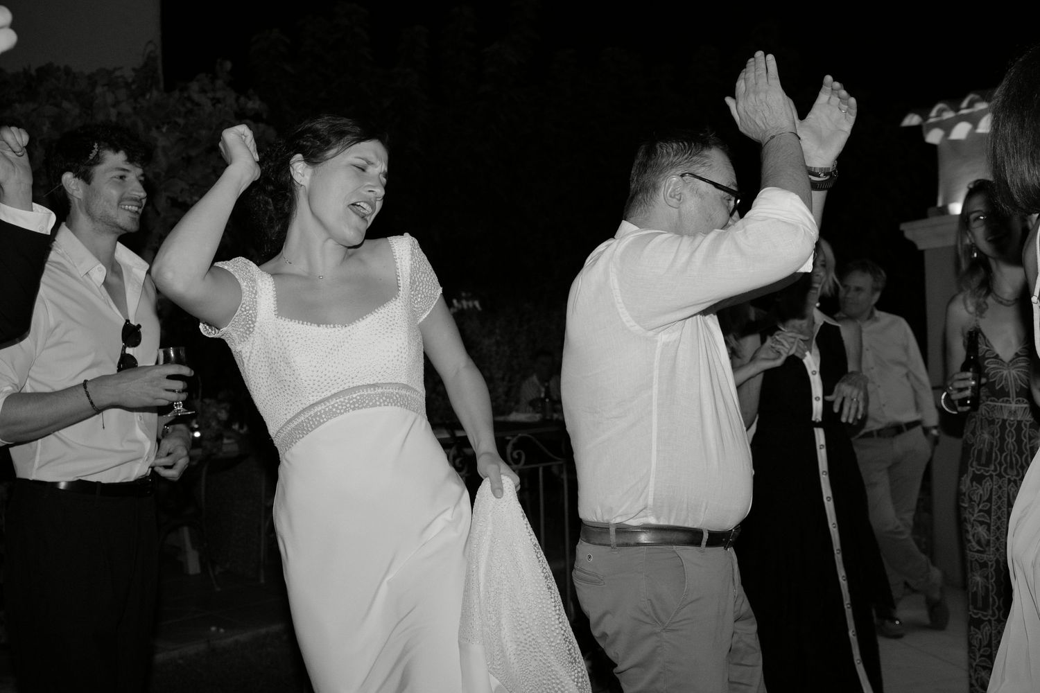 Augustine et les invités dansent pendant la soirée de mariage, en noir et blanc.